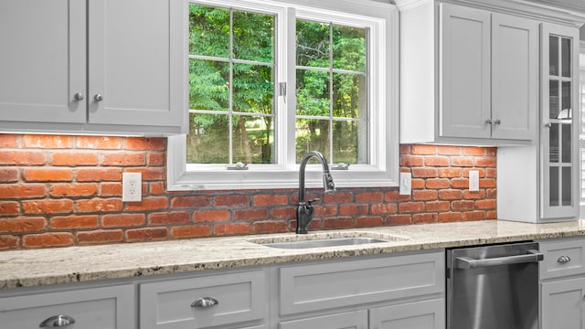 kitchen with backsplash, a wealth of natural light, sink, and light stone counters