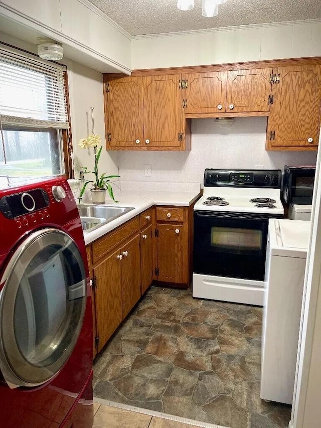 kitchen featuring electric range, brown cabinets, a sink, a textured ceiling, and washer / dryer