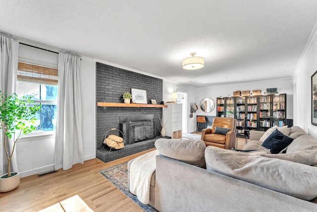 living room featuring light wood-style flooring, a brick fireplace, a textured ceiling, and baseboards