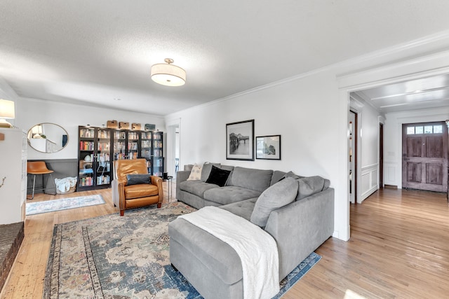 living room featuring a wainscoted wall, ornamental molding, and wood finished floors