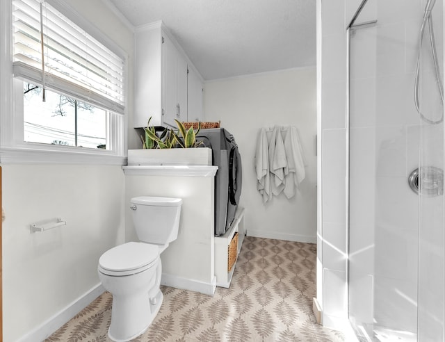 bathroom with an enclosed shower, toilet, baseboards, and separate washer and dryer