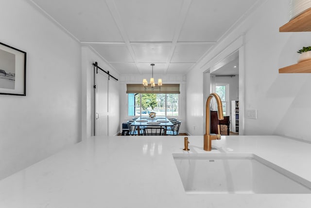 kitchen featuring coffered ceiling, an inviting chandelier, open shelves, a sink, and a barn door