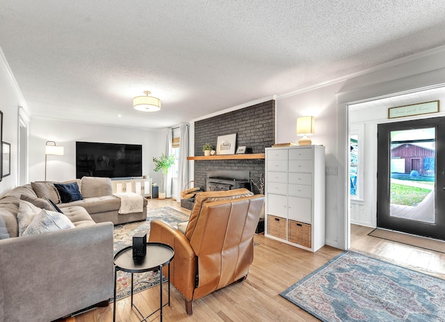 living room with a wealth of natural light, light wood-style flooring, a fireplace, and crown molding