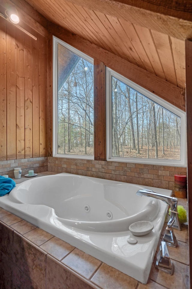 bathroom featuring vaulted ceiling, wood ceiling, plenty of natural light, and tiled tub