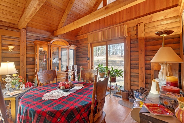 dining room with log walls, wood ceiling, hardwood / wood-style flooring, high vaulted ceiling, and beam ceiling