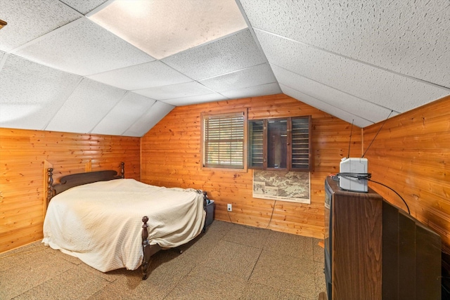 bedroom with lofted ceiling, a drop ceiling, and wooden walls