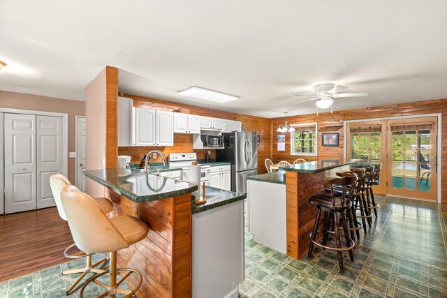 kitchen with a breakfast bar, appliances with stainless steel finishes, kitchen peninsula, and white cabinetry