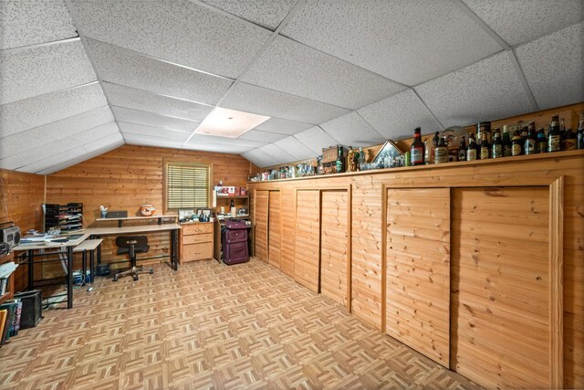 office area featuring a paneled ceiling, lofted ceiling, wooden walls, and light parquet floors