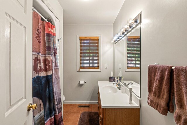 bathroom featuring tile patterned floors, vanity, a healthy amount of sunlight, and toilet