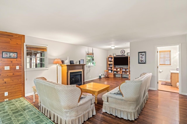 living room with dark hardwood / wood-style flooring, a wealth of natural light, and wooden walls