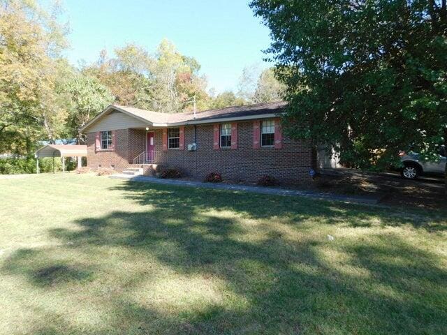 exterior space with a carport and a lawn