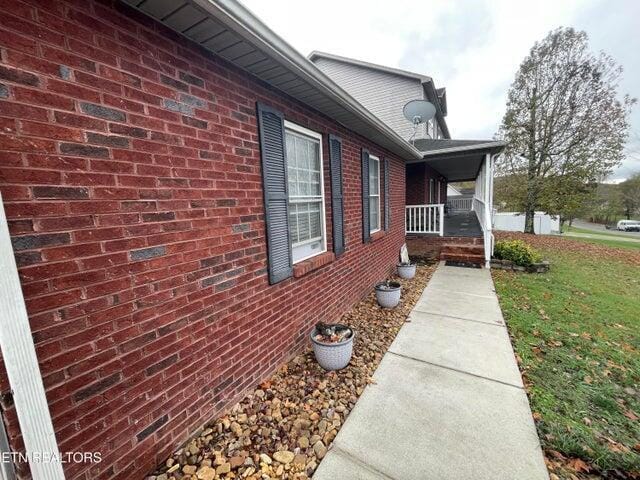 view of side of home featuring a porch and a yard