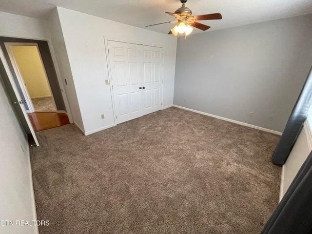 unfurnished bedroom with ceiling fan, dark carpet, and a closet