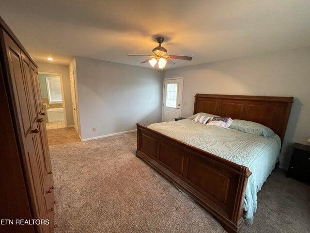 bedroom featuring ceiling fan, ensuite bath, and light carpet