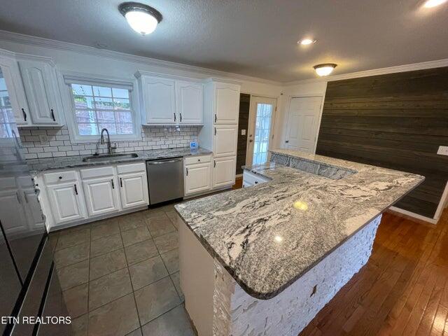 kitchen with stainless steel dishwasher, a center island, sink, and white cabinets