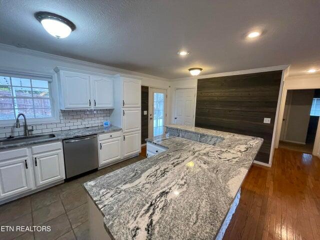 kitchen featuring white cabinetry, sink, stainless steel dishwasher, and a spacious island