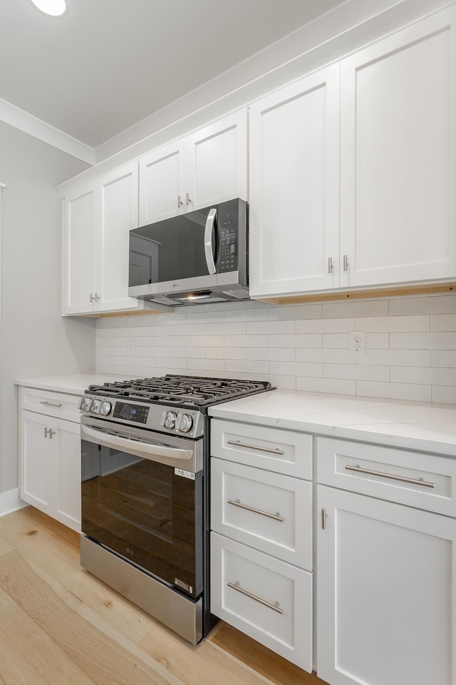 5118 Judd Way NW Unit 21, Cleveland, TN 37312 - kitchen with appliances with stainless steel finishes, decorative backsplash, white cabinetry, light wood-style flooring, and ornamental molding