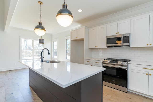 kitchen featuring appliances with stainless steel finishes, a sink, light wood-style flooring, and decorative backsplash