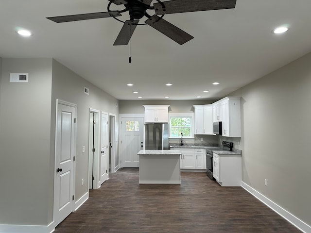 kitchen with ceiling fan, white cabinetry, dark wood-type flooring, a kitchen island, and appliances with stainless steel finishes