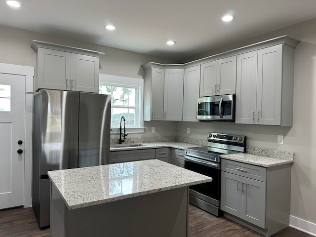 kitchen featuring a center island, sink, light stone countertops, dark hardwood / wood-style flooring, and stainless steel appliances