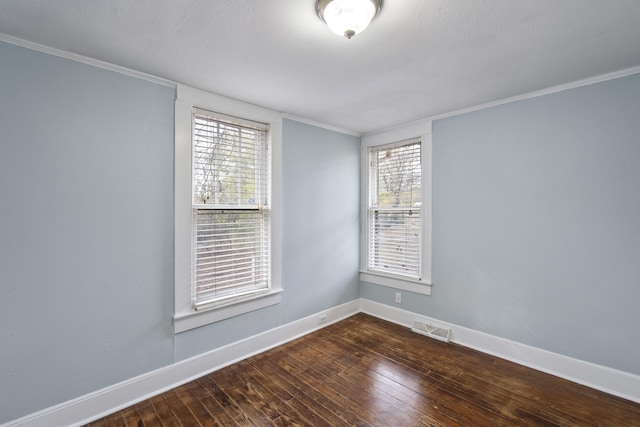 empty room with dark hardwood / wood-style flooring, a wealth of natural light, and crown molding