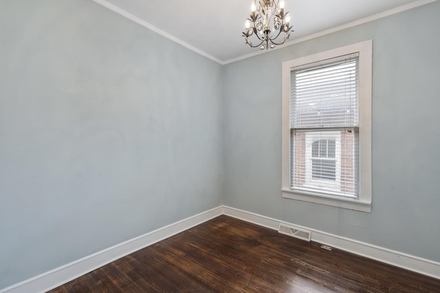 spare room featuring crown molding, dark wood-type flooring, and an inviting chandelier