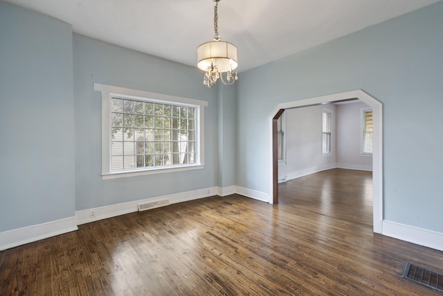 empty room featuring dark hardwood / wood-style floors and a notable chandelier