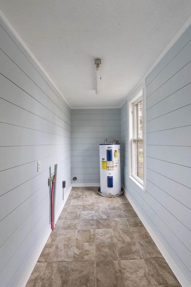 laundry area featuring wood walls and water heater