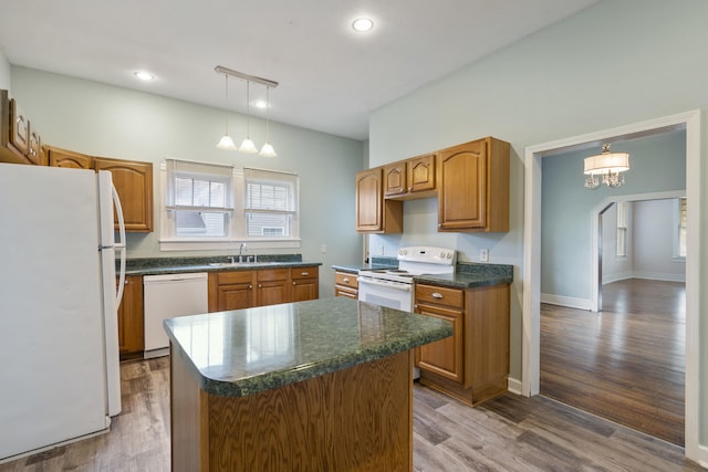 kitchen featuring white appliances, sink, decorative light fixtures, hardwood / wood-style flooring, and a center island