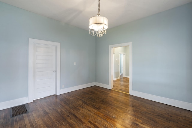 empty room with dark hardwood / wood-style floors and a chandelier