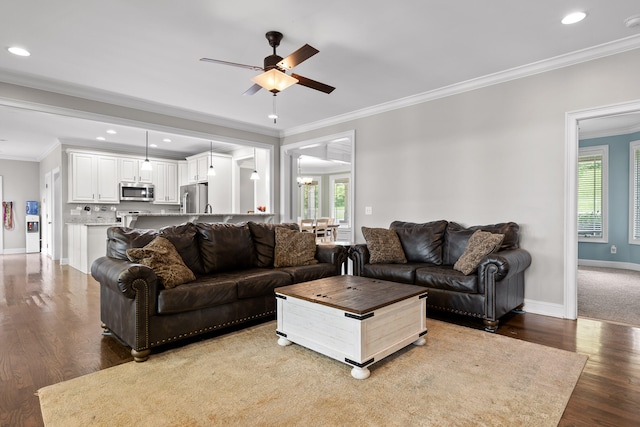 living room featuring hardwood / wood-style flooring, ceiling fan with notable chandelier, and ornamental molding