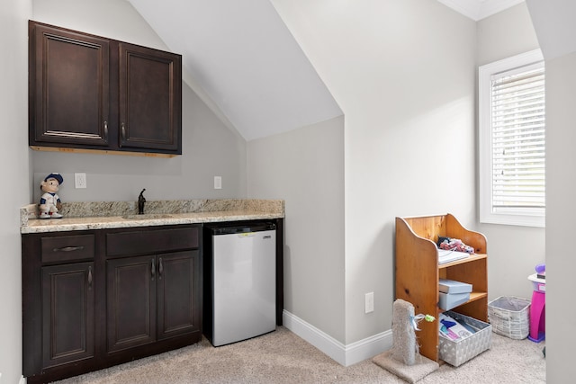 bar featuring lofted ceiling, dishwasher, light colored carpet, and dark brown cabinets