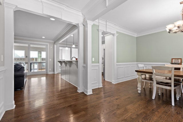 dining area with dark hardwood / wood-style flooring, an inviting chandelier, crown molding, and ornate columns