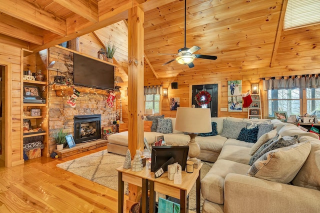 living room featuring ceiling fan, beamed ceiling, wood-type flooring, wooden walls, and wood ceiling