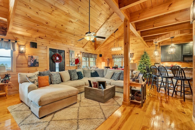 living room with light hardwood / wood-style floors, beam ceiling, wooden ceiling, and wooden walls