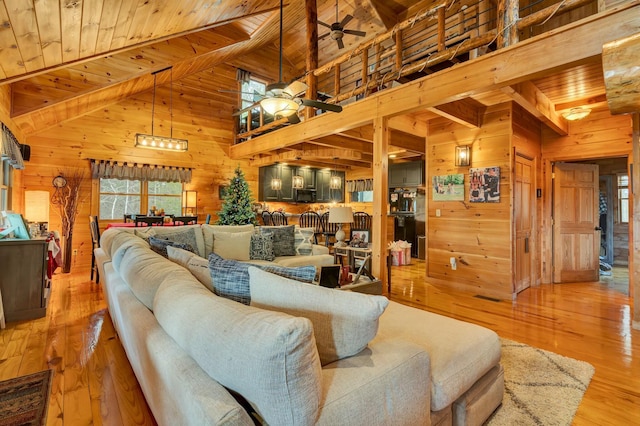 living room featuring a healthy amount of sunlight, wooden ceiling, light hardwood / wood-style flooring, high vaulted ceiling, and wooden walls