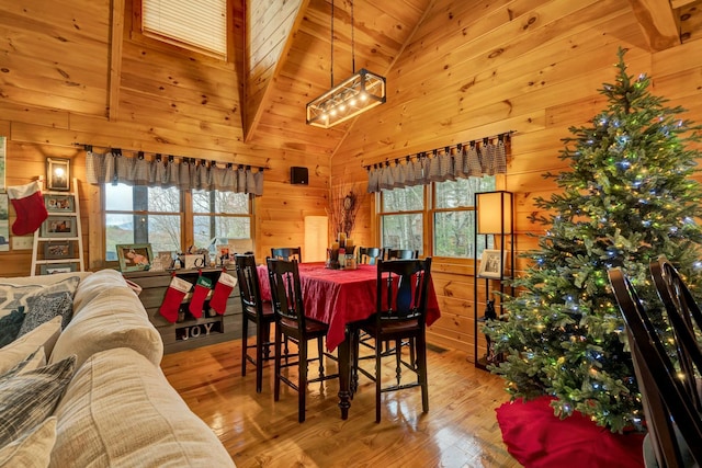 dining space featuring light wood-type flooring, high vaulted ceiling, wood ceiling, and wood walls