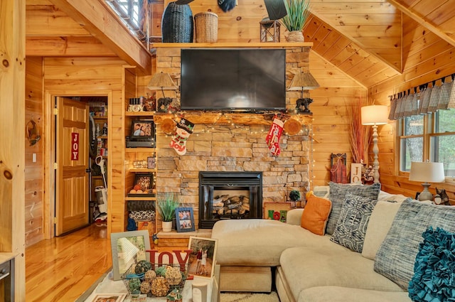 living room featuring hardwood / wood-style floors, a stone fireplace, and wooden walls