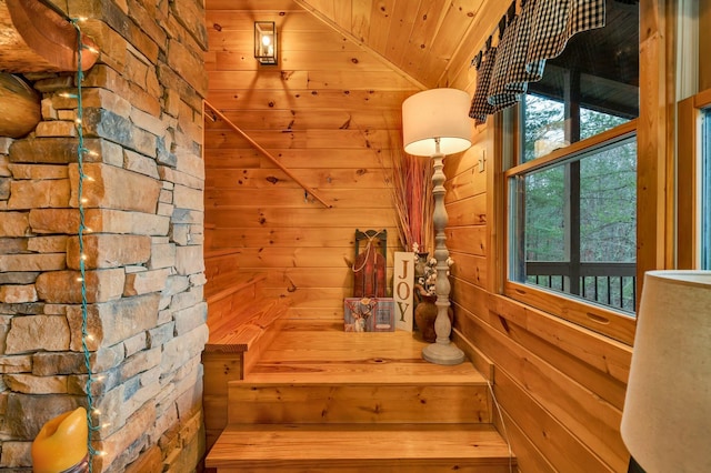 staircase with wooden walls, wood ceiling, and vaulted ceiling