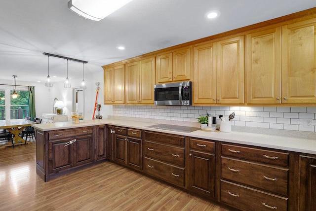 kitchen with kitchen peninsula, black electric stovetop, backsplash, pendant lighting, and light hardwood / wood-style flooring