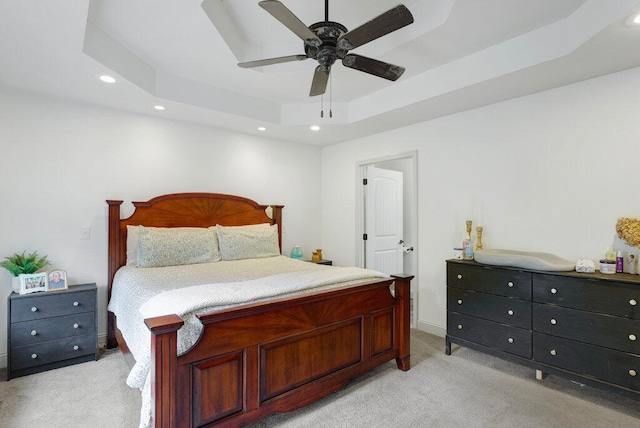 carpeted bedroom featuring a raised ceiling and ceiling fan