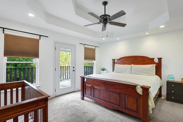 bedroom with light carpet, access to outside, a raised ceiling, and ceiling fan