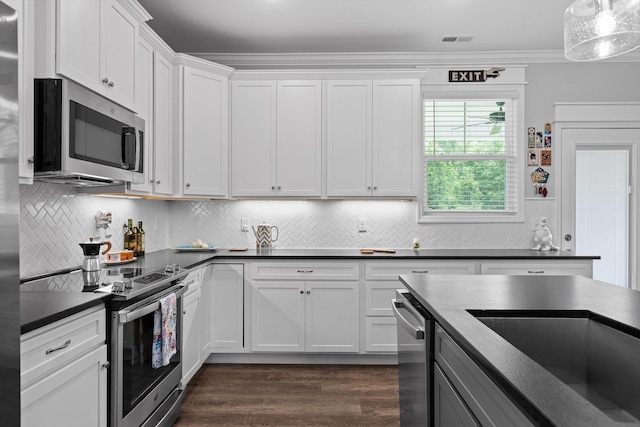 5086 Oop Rd, Chattanooga, TN 37416 - kitchen with appliances with stainless steel finishes, dark countertops, white cabinetry, decorative backsplash, and ornamental molding