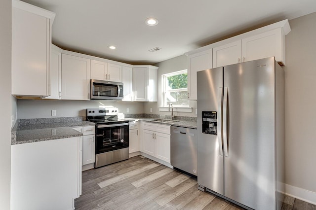 kitchen with white cabinets, light hardwood / wood-style floors, sink, and appliances with stainless steel finishes