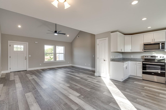 kitchen with light wood-type flooring, stainless steel appliances, white cabinetry, and lofted ceiling