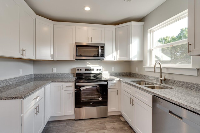 kitchen featuring sink, light hardwood / wood-style floors, light stone counters, white cabinetry, and stainless steel appliances