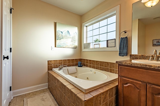 full bath with vanity, tile patterned floors, a tub with jets, and baseboards