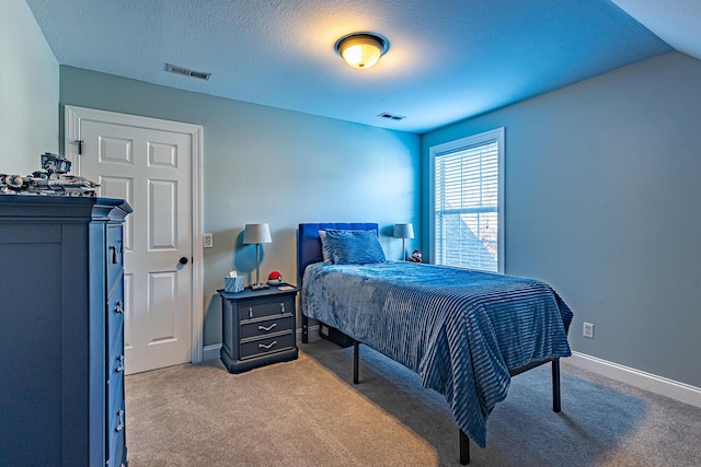 carpeted bedroom with visible vents, a textured ceiling, and baseboards