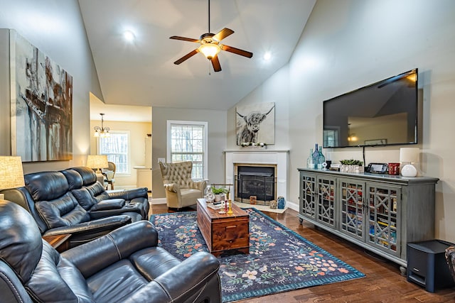 living room with high vaulted ceiling, ceiling fan with notable chandelier, wood finished floors, a fireplace, and baseboards