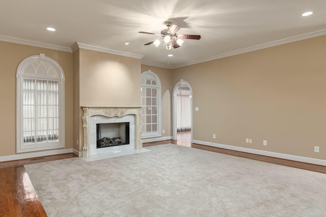 unfurnished living room featuring plenty of natural light, ceiling fan, crown molding, and a fireplace